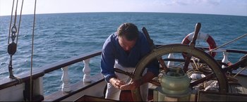 Movie still from “Dead Calm” (1989), directed by Phillip Noyce – A man on a boat looking at papers; Medium shot, High angle