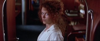 Movie still from “Dead Calm” (1989), directed by Phillip Noyce – A woman with red curly hair is looking at the camera; Close Up shot, Over the shoulder angle