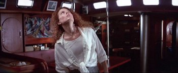 Movie still from “Dead Calm” (1989), directed by Phillip Noyce – A woman with red hair and a white shirt looking up; Medium shot, Low angle
