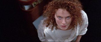 Movie still from “Dead Calm” (1989), directed by Phillip Noyce – A woman with red hair and blue eyes looking directly at the camera; Close Up shot, Overhead angle