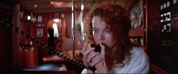 Movie still from “Dead Calm” (1989), directed by Phillip Noyce – A woman with red hair is holding a phone to her ear; Close Up shot, High angle