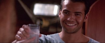 Movie still from “Dead Calm” (1989), directed by Phillip Noyce – A man smiling while holding a glass in his hand; Close Up shot, Low angle