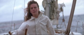 Movie still from “Dead Calm” (1989), directed by Phillip Noyce – A woman in a white jacket is standing on a boat; Medium shot, Low angle
