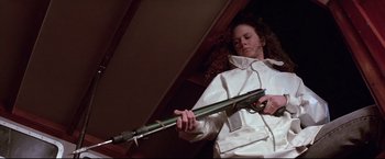 Movie still from “Dead Calm” (1989), directed by Phillip Noyce – A woman in a white jacket holding a rifle; Medium shot, Low angle