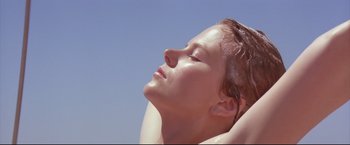 Movie still from “Dead Calm” (1989), directed by Phillip Noyce – A woman with her eyes closed with her hands behind her head; Close Up shot, Low angle