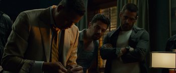 Movie still from “Dead Man Down” (2013), directed by Niels Arden Oplev – A group of men standing next to each other in a room; Medium shot, Low angle