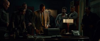 Movie still from “Dead Man Down” (2013), directed by Niels Arden Oplev – A group of men standing around a table; Medium shot, Low angle