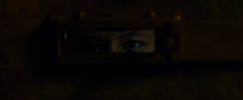 Movie still from “Dead Man Down” (2013), directed by Niels Arden Oplev – A person's eyes are seen through a wooden fence; Extreme Close Up shot, Overhead angle