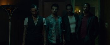 Movie still from “Dead Man Down” (2013), directed by Niels Arden Oplev – A group of men standing next to each other in a room; Medium shot, Low angle