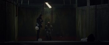 Movie still from “Dead Man Down” (2013), directed by Niels Arden Oplev – Two men sitting in a dark room with a light shining on them; Wide shot, Low angle