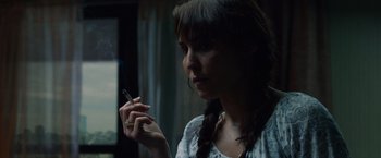 Movie still from “Dead Man Down” (2013), directed by Niels Arden Oplev – A woman smoking a cigarette while holding a cell phone in her hand; Close Up shot, Over the shoulder angle