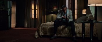 Movie still from “Dead Man Down” (2013), directed by Niels Arden Oplev – A man sitting on top of a bed looking at his cell phone; Medium shot, Low angle