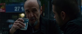 Movie still from “Dead Man Down” (2013), directed by Niels Arden Oplev – An older man holding a coffee cup while talking to a younger man; Close Up shot, Over the shoulder angle