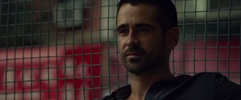 Movie still from “Dead Man Down” (2013), directed by Niels Arden Oplev – A person wearing a black shirt near a fence; Close Up shot, Over the shoulder angle