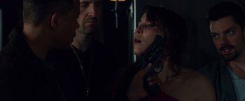 Movie still from “Dead Man Down” (2013), directed by Niels Arden Oplev – A woman holding a gun in her hand while standing next to two other men; Close Up shot, Over the shoulder angle