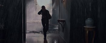 Movie still from “Dead Man Down” (2013), directed by Niels Arden Oplev – A man walking down a wet walkway in the rain; Wide shot, Low angle