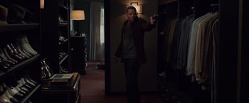 Movie still from “Dead Man Down” (2013), directed by Niels Arden Oplev – A man holding a handgun in a dark room; Medium shot, Over the shoulder angle