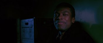 Movie still from “Dead Presidents” (1995), directed by Albert Hughes – A young man smiling for the camera in a dark room; Close Up shot, Low angle