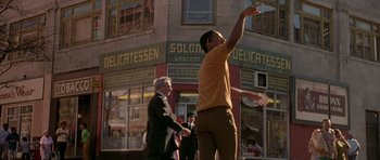 Movie still from “Dead Presidents” (1995), directed by Albert Hughes – A man in a yellow shirt is throwing a frisbee; Wide shot, Low angle