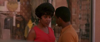 Movie still from “Dead Presidents” (1995), directed by Albert Hughes – A woman in a red dress talking to a man in an orange shirt; Close Up shot, Over the shoulder angle