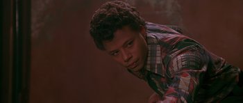 Movie still from “Dead Presidents” (1995), directed by Albert Hughes – A young man in a plaid shirt leaning against a wall; Close Up shot, Low angle
