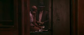 Movie still from “Dead Presidents” (1995), directed by Albert Hughes – Two men in suits and a hat are talking on the phone; Medium shot, Low angle