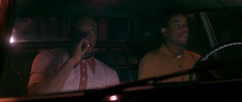 Movie still from “Dead Presidents” (1995), directed by Albert Hughes – Two men sitting in the back seat of a car; Medium shot, Low angle