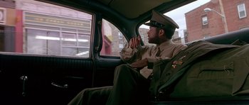 Movie still from “Dead Presidents” (1995), directed by Albert Hughes – A man sitting in the back seat of a car; Medium shot, Low angle