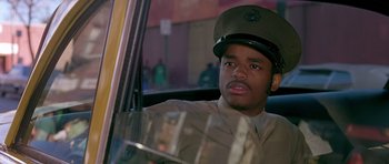 Movie still from “Dead Presidents” (1995), directed by Albert Hughes – A man wearing a hat sitting in the driver's seat of a car; Close Up shot, Over the shoulder angle