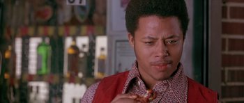 Movie still from “Dead Presidents” (1995), directed by Albert Hughes – A young man eating a piece of pizza in a restaurant; Close Up shot, Low angle