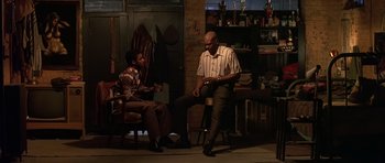 Movie still from “Dead Presidents” (1995), directed by Albert Hughes – Two men are sitting in a living room; Wide shot, Low angle