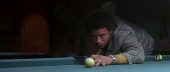 A man leaning over a pool table looking at an apple
