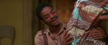 Movie still from “Dead Presidents” (1995), directed by Albert Hughes – A young man holding onto an umbrella while smiling; Close Up shot, High angle