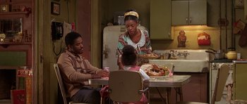 Movie still from “Dead Presidents” (1995), directed by Albert Hughes – A family sitting at a table with a plate of food on it; Medium shot, High angle