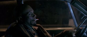 Movie still from “Dead Presidents” (1995), directed by Albert Hughes – A man sitting in the driver's seat of a car while smoking a cigarette; Close Up shot, Low angle