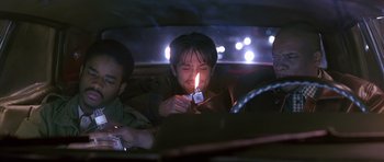 Movie still from “Dead Presidents” (1995), directed by Albert Hughes – A man lighting a candle in the middle of the road; Medium shot, Low angle