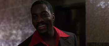 Movie still from “Dead Presidents” (1995), directed by Albert Hughes – A person wearing a suit and smiling; Close Up shot, Low angle