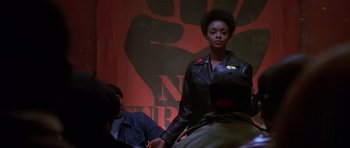 Movie still from “Dead Presidents” (1995), directed by Albert Hughes – A woman in a leather jacket holding hands with a man; Medium shot, Low angle