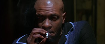 Movie still from “Dead Presidents” (1995), directed by Albert Hughes – A bald man smoking a cigarette in a dark room; Close Up shot, Low angle
