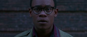 Movie still from “Dead Presidents” (1995), directed by Albert Hughes – A person wearing glasses and a jacket; Close Up shot, Low angle
