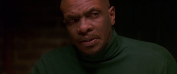 Movie still from “Dead Presidents” (1995), directed by Albert Hughes – A man with a bald head wearing a green shirt; Close Up shot, Low angle