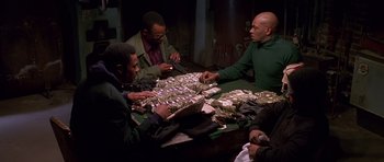 Movie still from “Dead Presidents” (1995), directed by Albert Hughes – A group of men sitting around a table with money; Medium shot, High angle