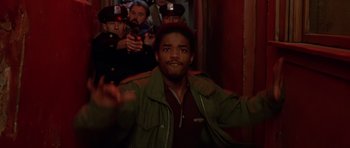 Movie still from “Dead Presidents” (1995), directed by Albert Hughes – A man in a green jacket and a crowd of onlookers; Medium shot, Low angle