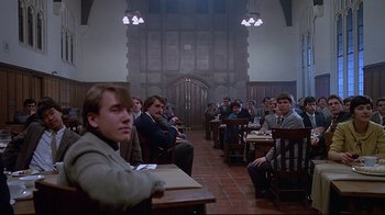 Movie still from “Dead Ringers” (1988), directed by David Cronenberg – A group of people sitting at a table in a room; Wide shot, High angle