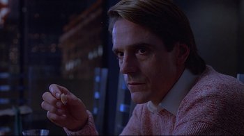 Movie still from “Dead Ringers” (1988), directed by David Cronenberg – A man holding something in his hand while looking at the camera; Close Up shot, Low angle