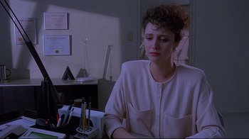 Movie still from “Dead Ringers” (1988), directed by David Cronenberg – A woman sitting at a desk in front of a computer; Medium shot, Over the shoulder angle