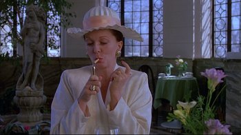 Movie still from “Dead Ringers” (1988), directed by David Cronenberg – A woman wearing a hat and holding a toothbrush in her mouth; Medium shot, Low angle