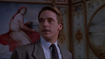 Movie still from “Dead Ringers” (1988), directed by David Cronenberg – A man in a suit and tie in front of a painting; Close Up shot, Low angle