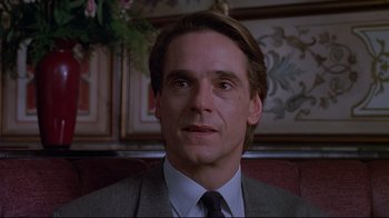 Movie still from “Dead Ringers” (1988), directed by David Cronenberg – A man in a suit and tie sitting in a chair; Close Up shot, Low angle