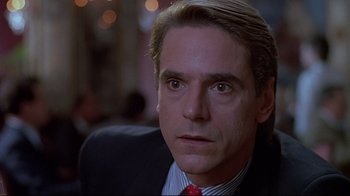 Movie still from “Dead Ringers” (1988), directed by David Cronenberg – A man in a suit and red tie looking into the camera; Close Up shot, Over the shoulder angle